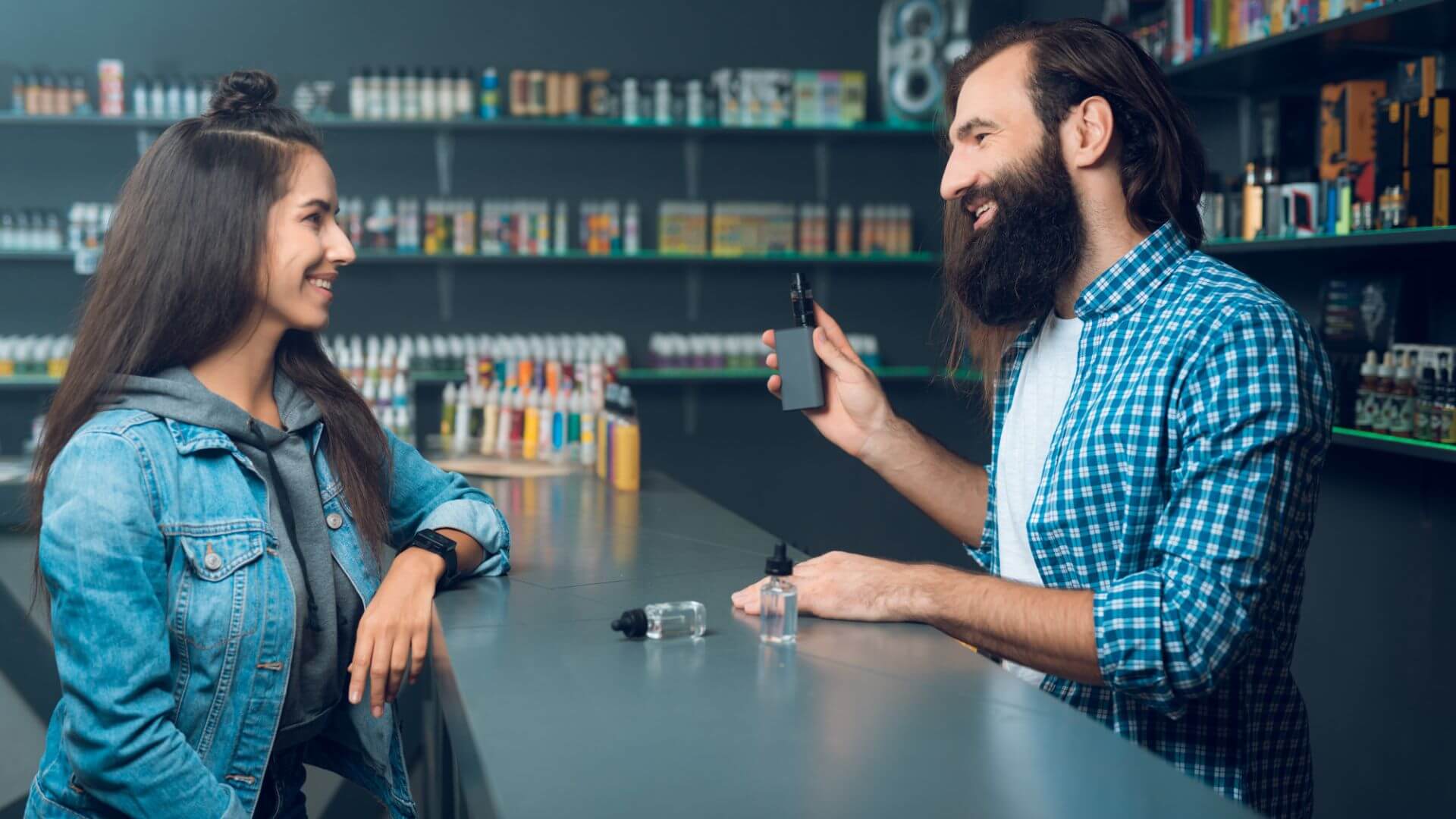 A girl listening to the sales man in cigarette shop to introduce her on choosing good vape device